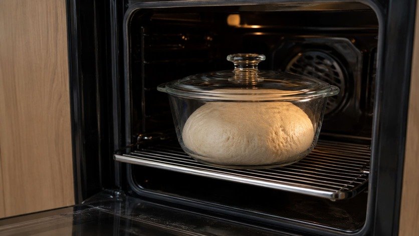 Bread dough proving in a covered glass container inside a switched-off oven